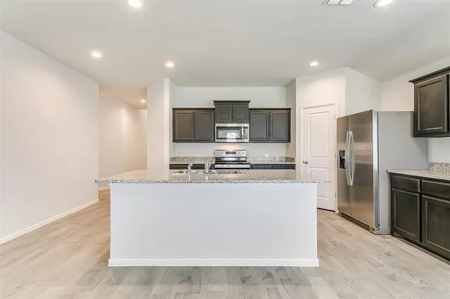 a large kitchen with stainless steel appliances a refrigerator a stove a sink a microwave and cabinets