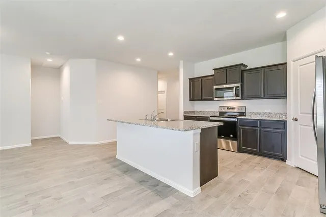 a kitchen with kitchen island stainless steel appliances a sink stove and refrigerator