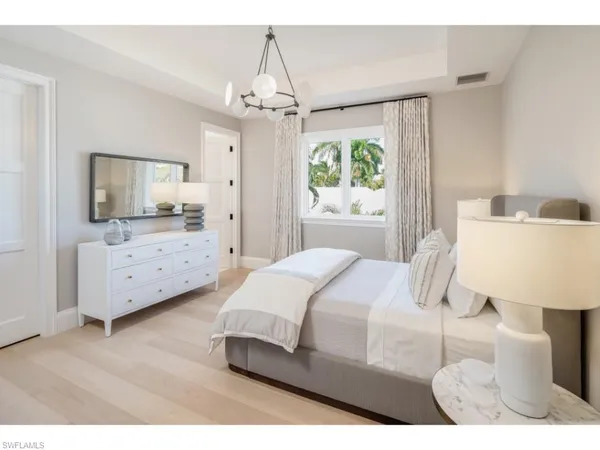 a bedroom with a bed a chandelier and flat screen tv