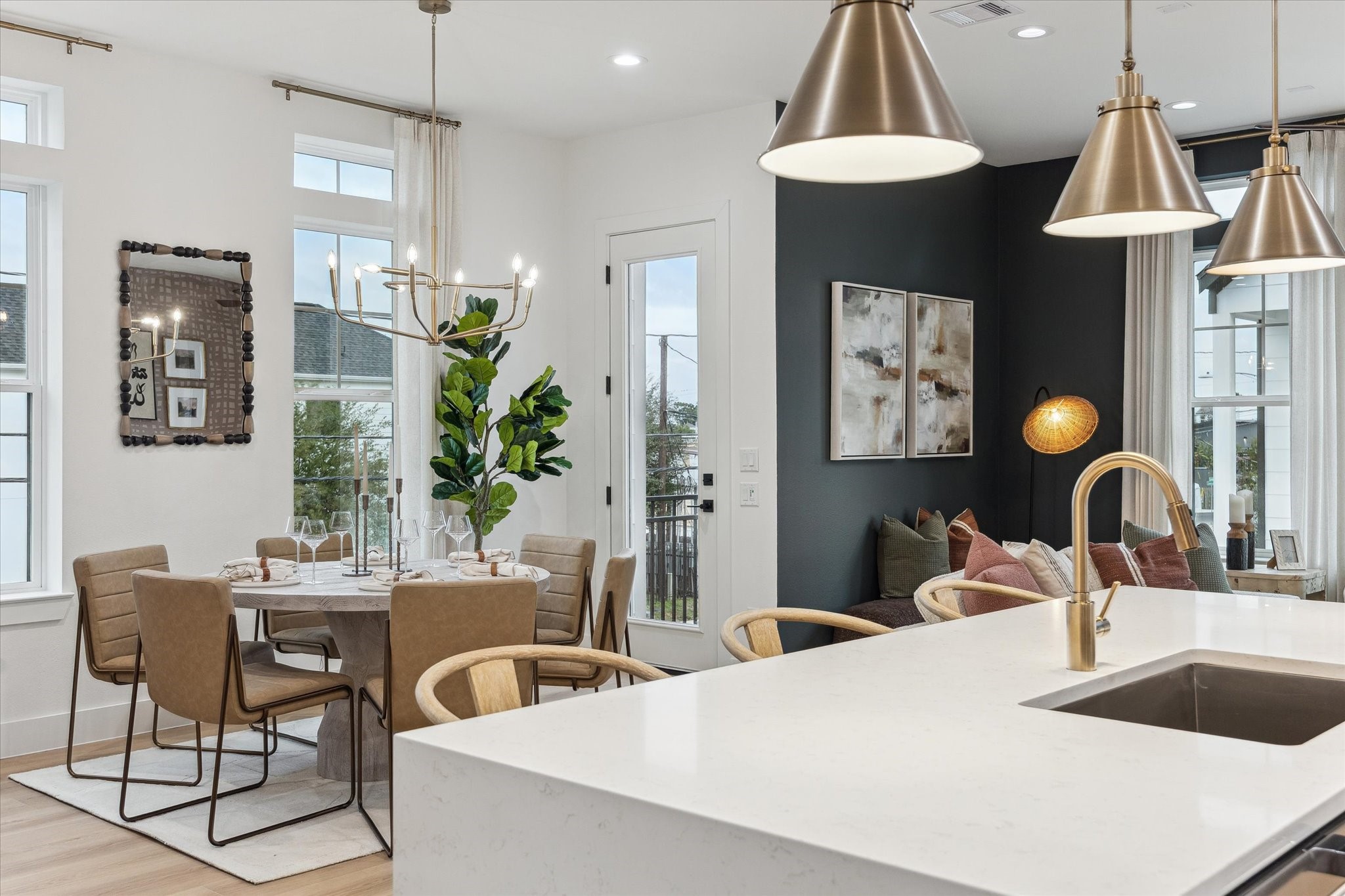 752 Curtin Street Houston, TX 77018 - Photo 17 of 37 Elegant open-concept dining and living area featuring a modern kitchen island with gold fixtures, chic pendant lighting, and a cozy seating nook. Large windows and a stylish chandelier enhance the airy ambiance.