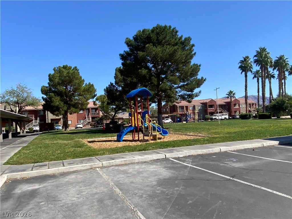 4730 East Craig Road, Unit 2029 Las Vegas, NV 89115 - Photo 2 of 4 A vibrant playground anchors this community's recreational space, bordered by mature trees and residential buildings.