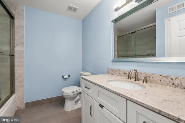 a bathroom with a granite countertop sink a large mirror and toilet