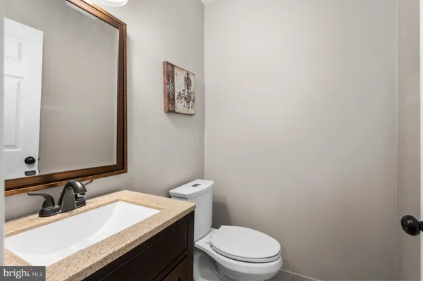 a bathroom with a granite countertop sink mirror vanity and toilet