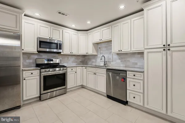 a kitchen with stainless steel appliances granite countertop a stove a sink and a microwave