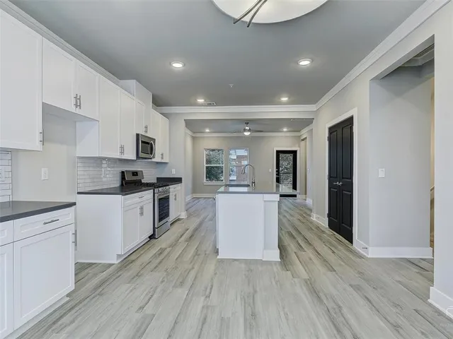 a large kitchen with kitchen island white cabinets and stainless steel appliances