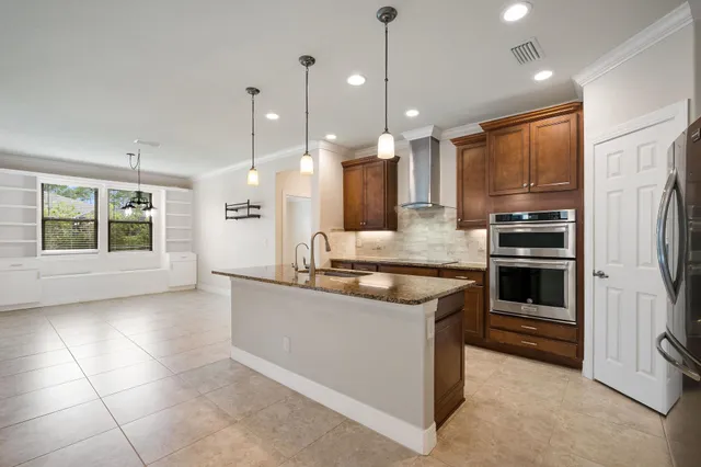a large kitchen with kitchen island a large counter top stainless steel appliances and cabinets