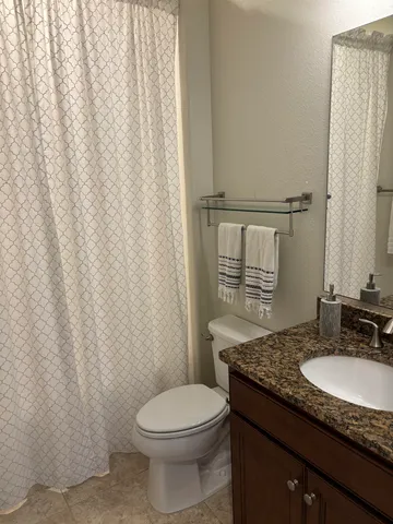 a bathroom with a granite countertop toilet sink and mirror