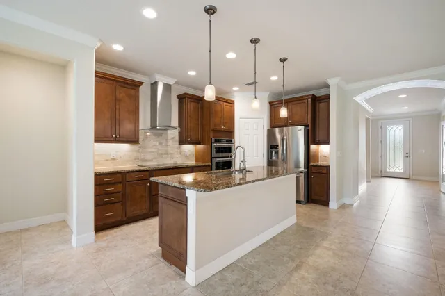 a large kitchen with stainless steel appliances kitchen island a large counter top and a refrigerator
