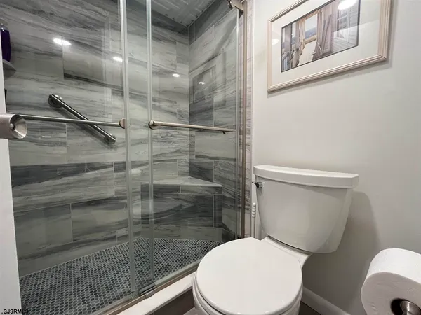 a bathroom with a granite countertop toilet a sink a mirror and a shower