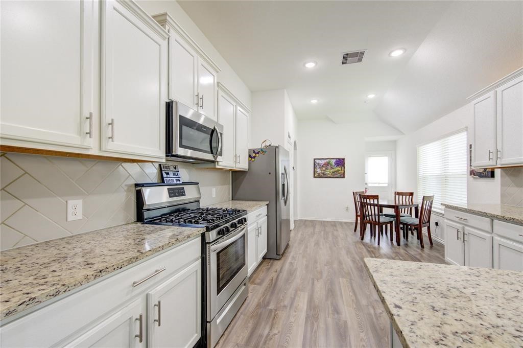 25519 Pitchfork Ranch Place Katy, TX 77493 - Photo 12 of 31 a kitchen with stainless steel appliances granite countertop a stove top oven a sink a dining table and chairs with wooden floor