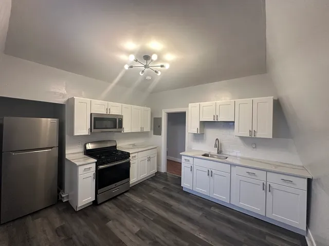 a kitchen with refrigerator a sink and wooden floor