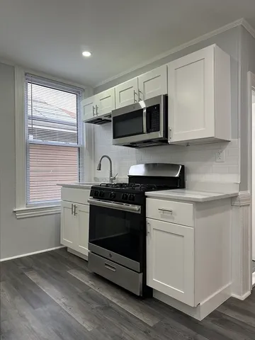 a kitchen with stainless steel appliances white cabinets and a stove top oven