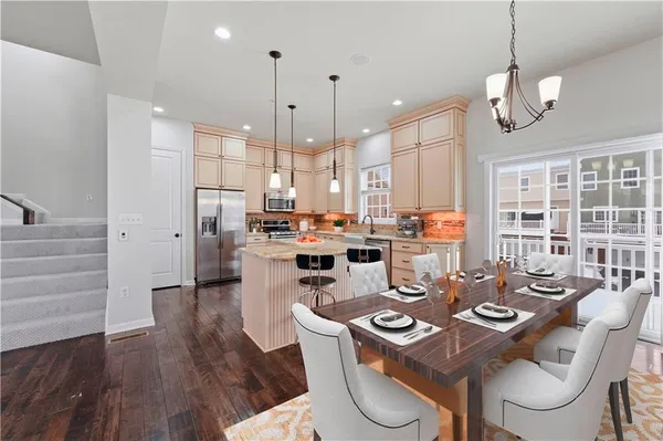 a dining room with stainless steel appliances kitchen island granite countertop a table chairs and a kitchen view