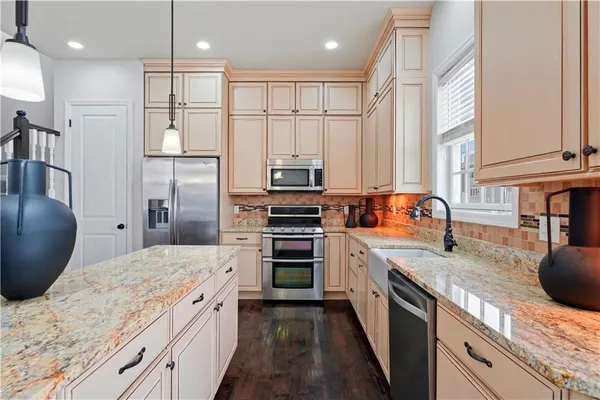 a large kitchen with stainless steel appliances granite countertop a stove a sink and a refrigerator