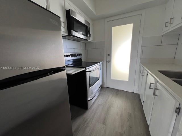 1350 East Sample Road, Unit 306 Pompano Beach, FL 33064 - Photo 1 of 13 a kitchen with stainless steel appliances a sink a stove top oven a wooden floor and cabinets