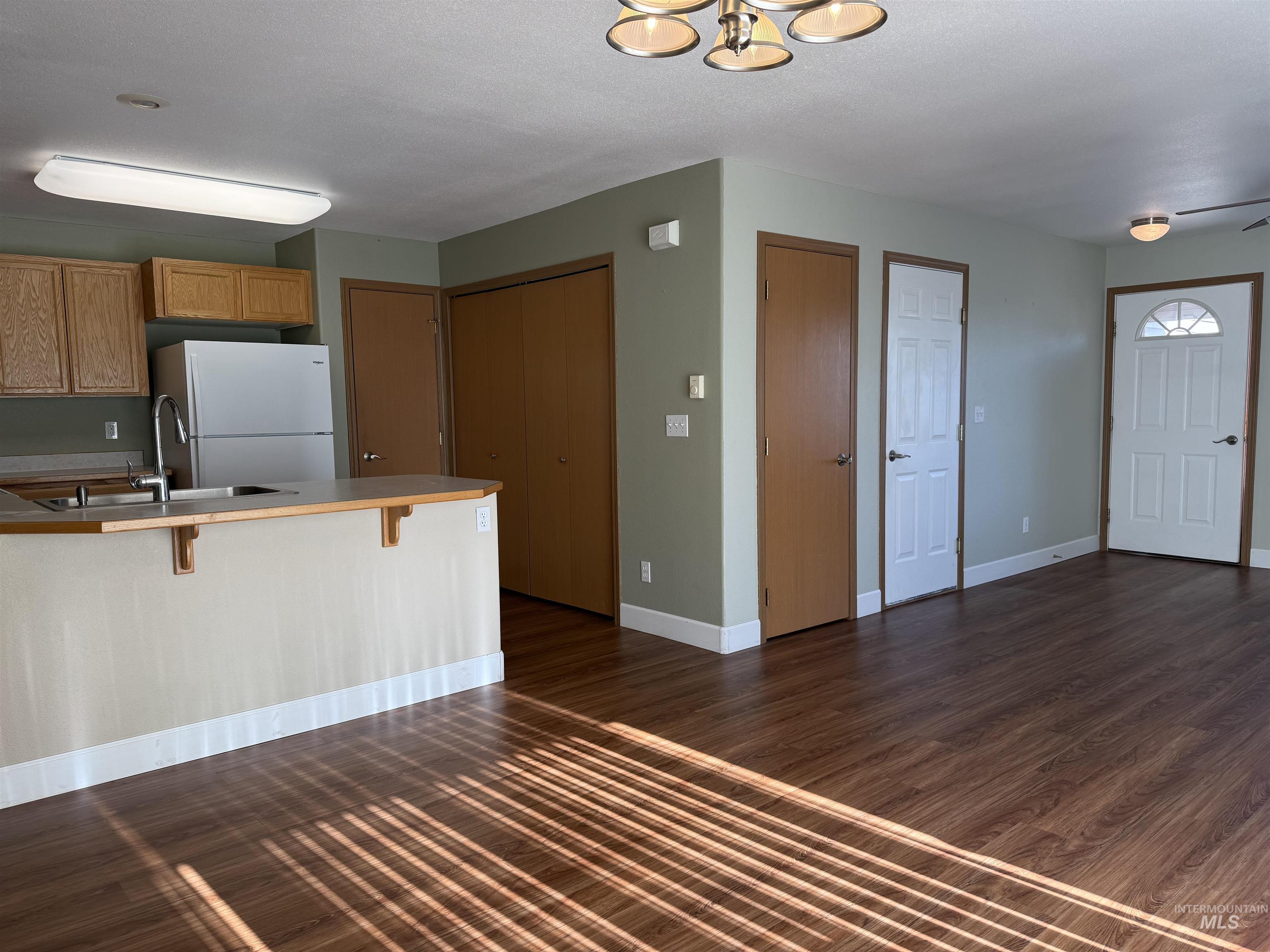 257 Pintail Lane Moscow, ID 83843 - Photo 4 of 28 Kitchen with a breakfast bar, a peninsula, wood finish cabinets, freestanding refrigerator, and dark wood-style floors