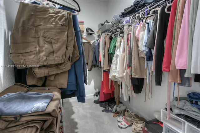 a view of walk in closet with clothes and shoes