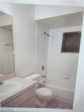 a bathroom with a granite countertop sink a toilet a mirror and bathtub