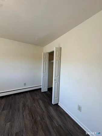 a view of an empty room with wooden floor and closet