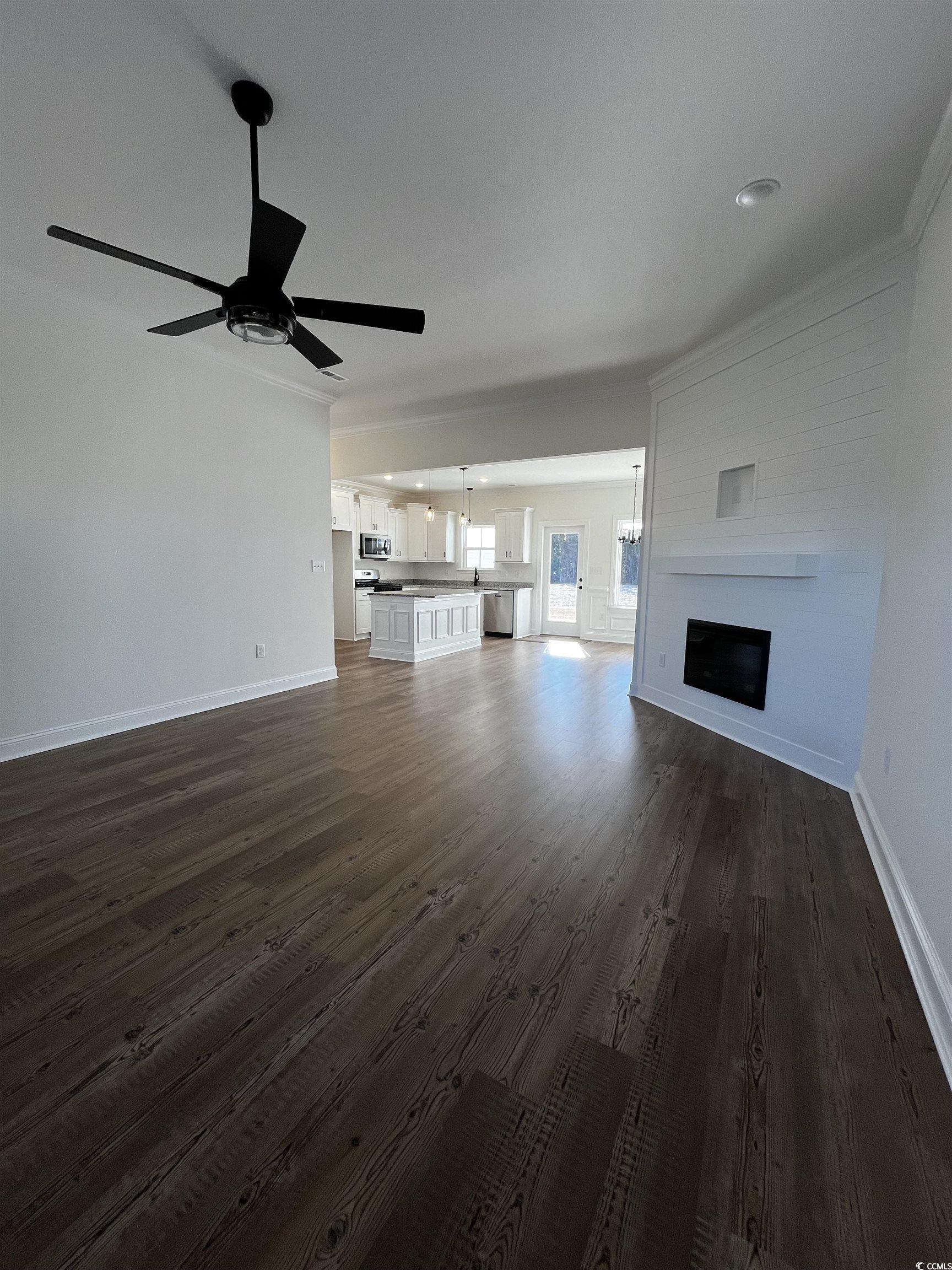 3440 Asbury Road Aynor, SC 29511 - Photo 2 of 9 Unfurnished living room with a large fireplace, dark wood-type flooring, crown molding, and ceiling fan