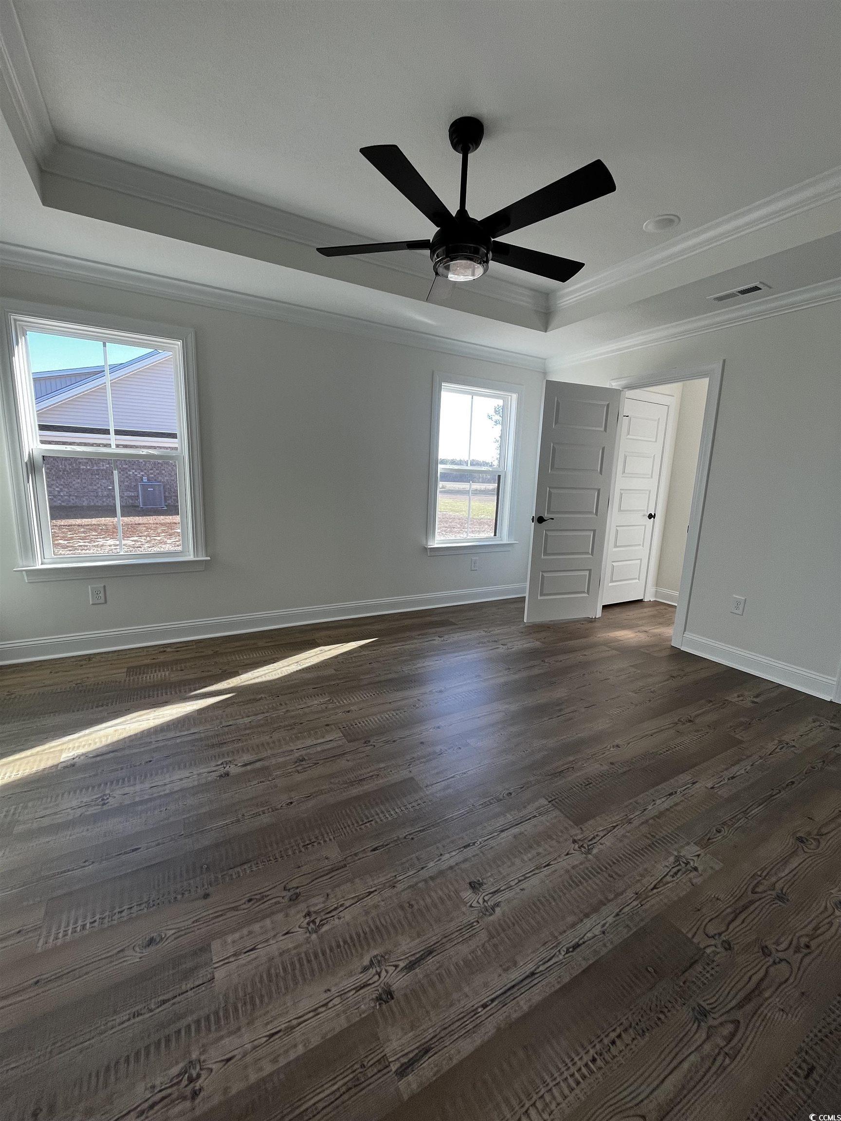 3440 Asbury Road Aynor, SC 29511 - Photo 4 of 9 Unfurnished bedroom with crown molding, a tray ceiling, a ceiling fan, and dark wood finished floors