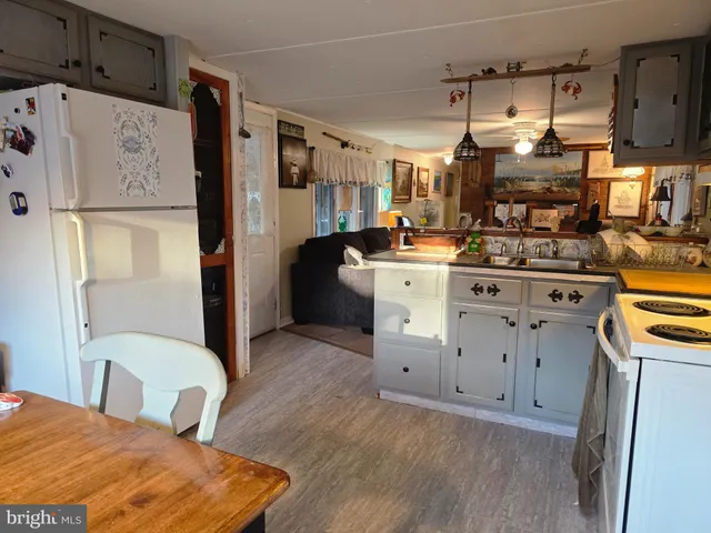 a kitchen with stainless steel appliances granite countertop a refrigerator a stove a sink dishwasher and white cabinets with wooden floor