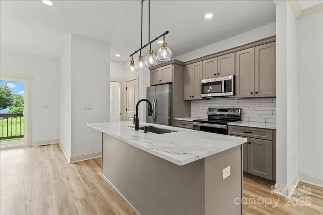 a kitchen with kitchen island granite countertop a sink appliances cabinets and a counter top space