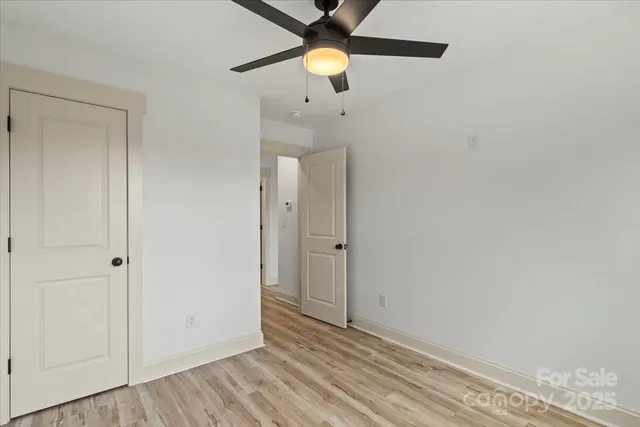 a view of kitchen and empty room with wooden floor