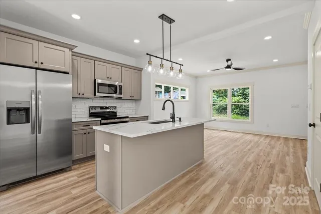 a kitchen with kitchen island white cabinets stainless steel appliances and a window
