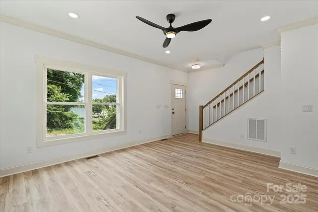 a view of empty room with wooden floor and fan
