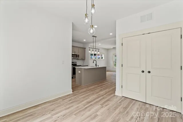 a view of kitchen and empty room with wooden floor