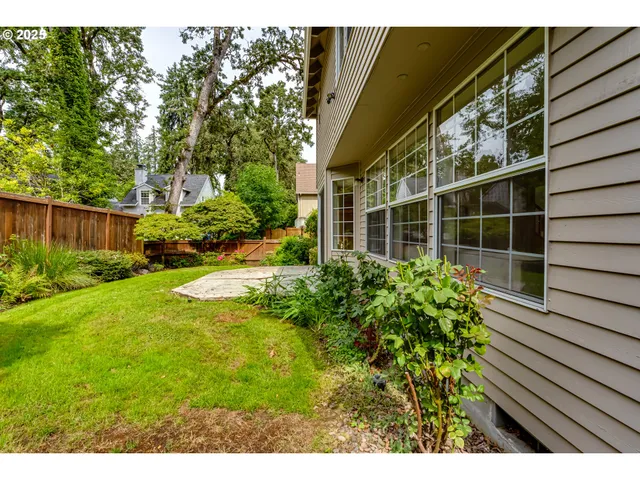 a view of backyard with potted plants and floor to ceiling window and wooden fence