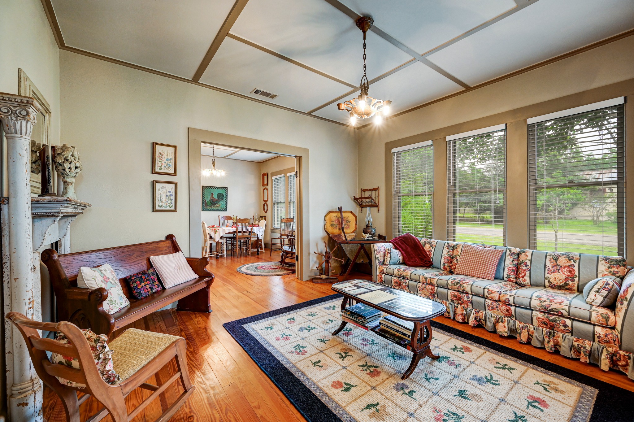 719 Elm Street Blanco, TX 78606 - Photo 8 of 25 Living area featuring polished wood flooring, a coffered ceiling, multiple windows, an overhead light fixture, and an archway opening to an additional room