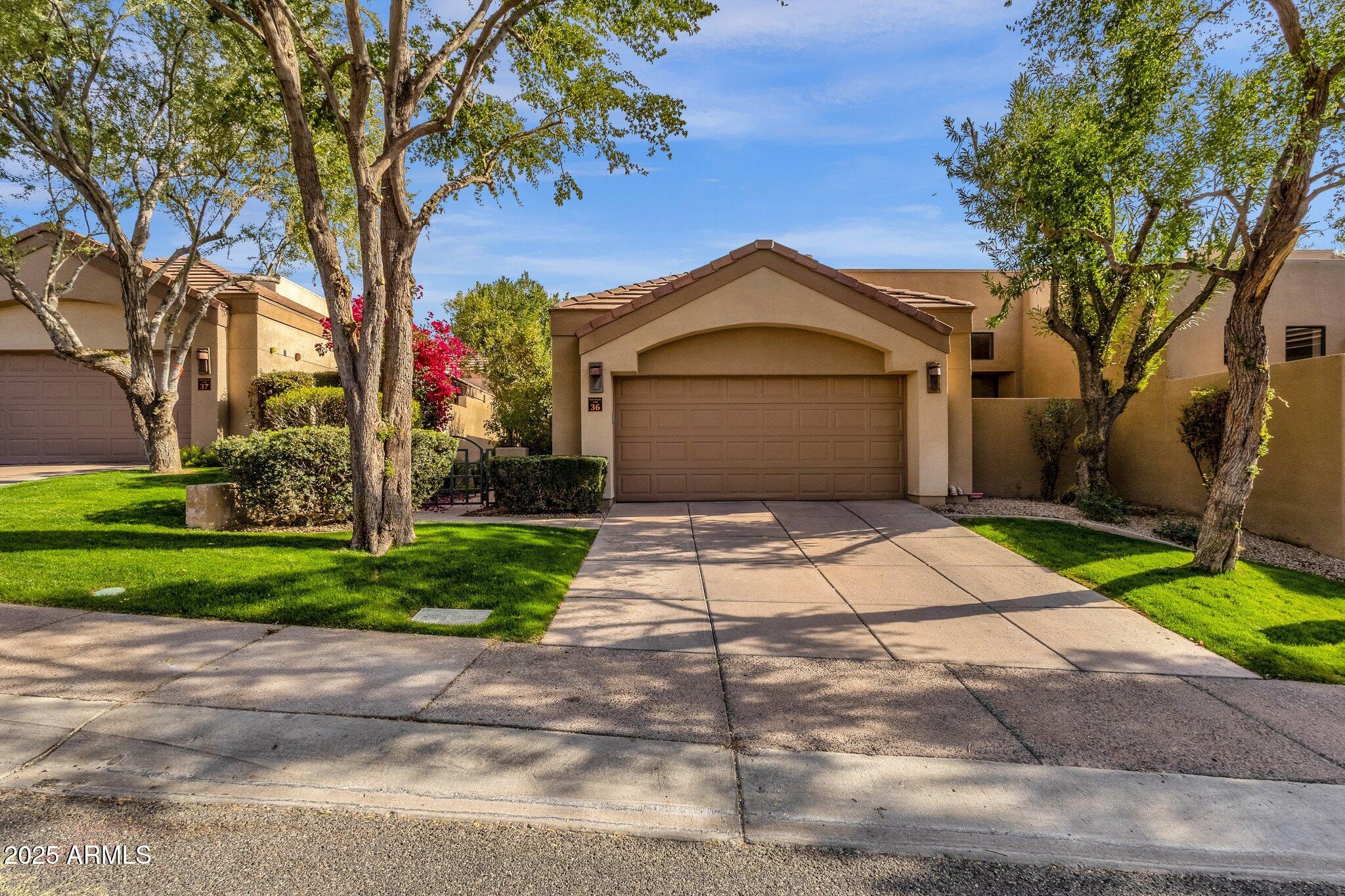7740 East Gainey Ranch Road, Unit 36 Scottsdale, AZ 85258 - Photo 1 of 54 a front view of a house with a yard and garage