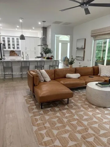 a living room with couches and kitchen view with wooden floor