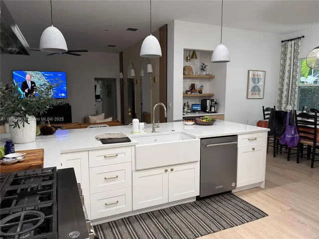 a kitchen with stainless steel appliances a stove a sink and a flat screen tv