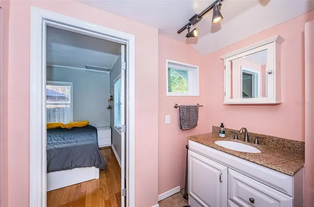 a en suite bathroom with a granite countertop sink and a mirror