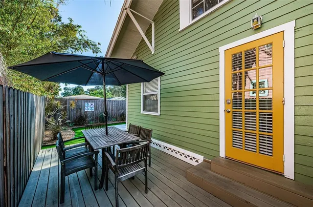 a view of a deck with table and chairs under an umbrella with wooden floor