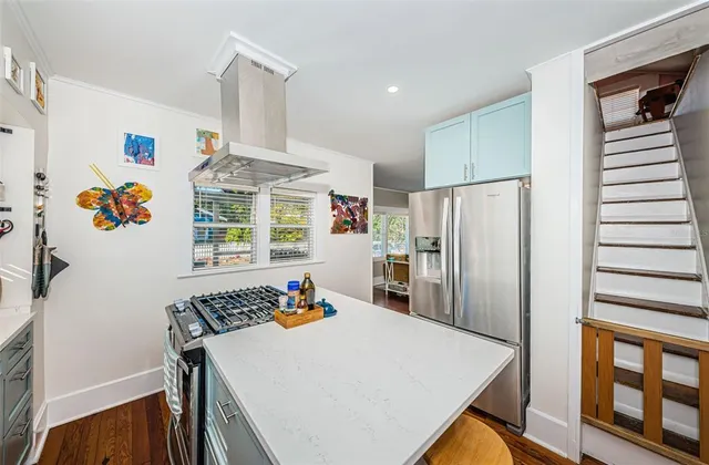 a kitchen with stainless steel appliances granite countertop a refrigerator a stove a sink dishwasher and a dining table with wooden floor