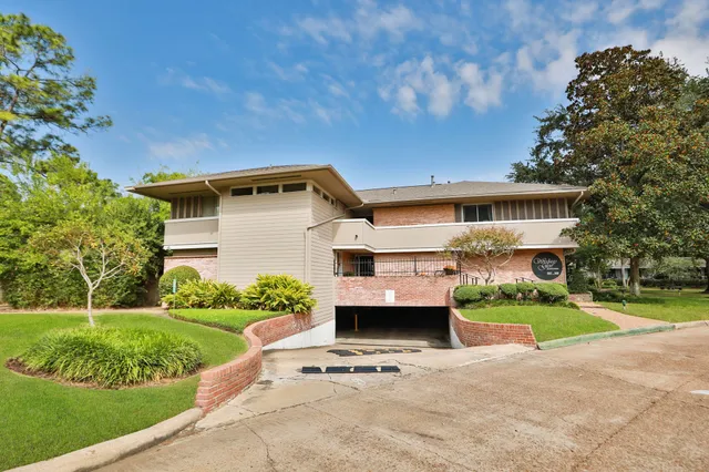 a front view of a house with a garden and trees
