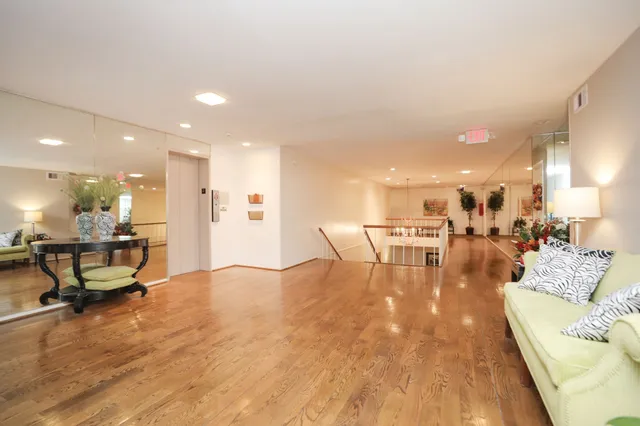 a kitchen with a sink dishwasher a refrigerator and white cabinets with wooden floors