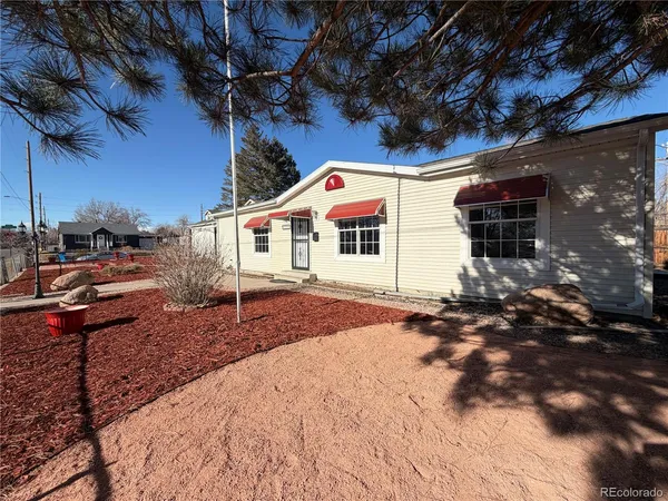 a view of a white house with a large tree