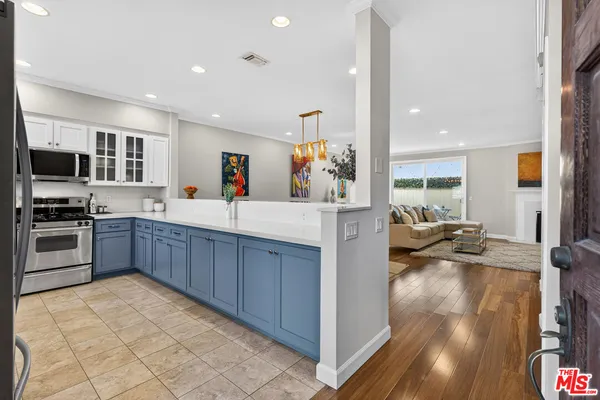 a kitchen with stainless steel appliances a sink a stove top oven a chimney and a center island