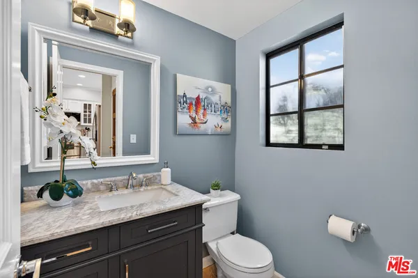 a bathroom with a granite countertop sink mirror vanity and toilet