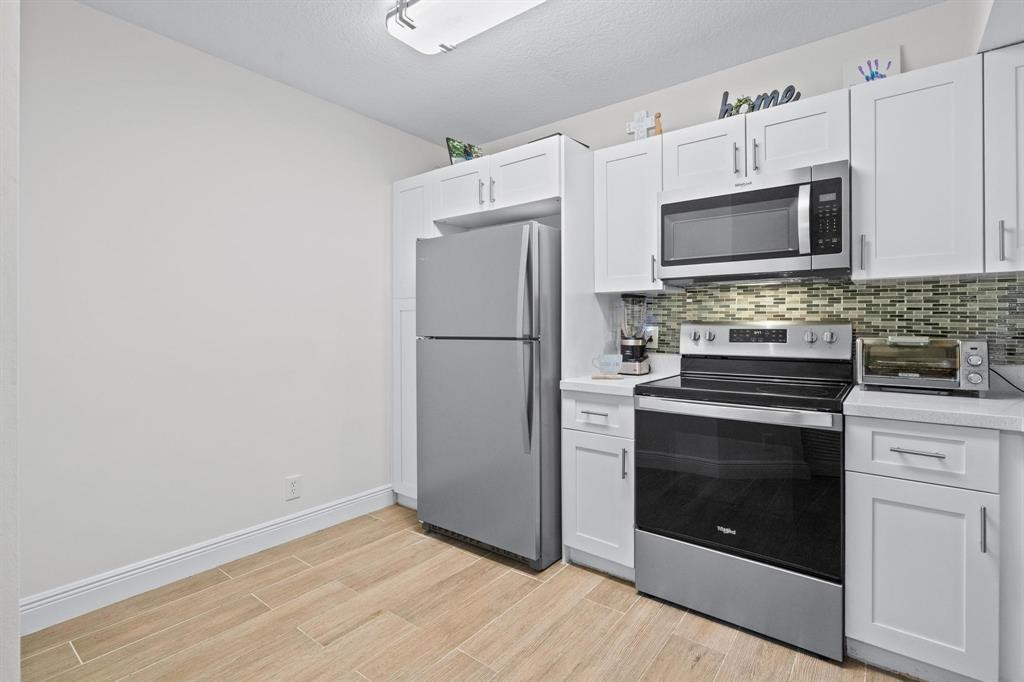 a kitchen with granite countertop white cabinets stainless steel appliances and wooden floor