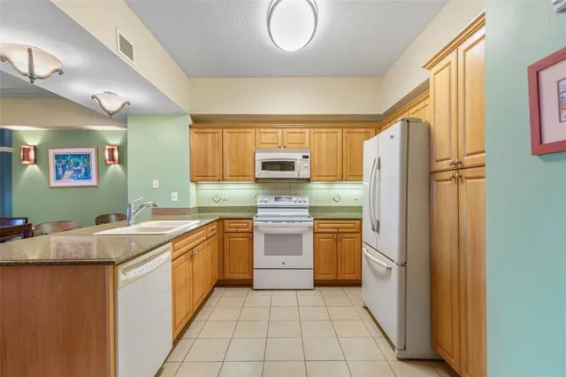a kitchen with stainless steel appliances granite countertop a stove refrigerator and chairs