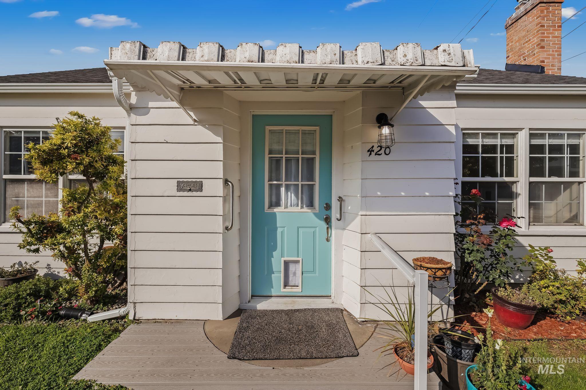 420 4th Street Lewiston, ID 83501 - Photo 2 of 38 White siding exterior with a light blue entry door, an overhead decorative trellis, and an exterior wall light fixture