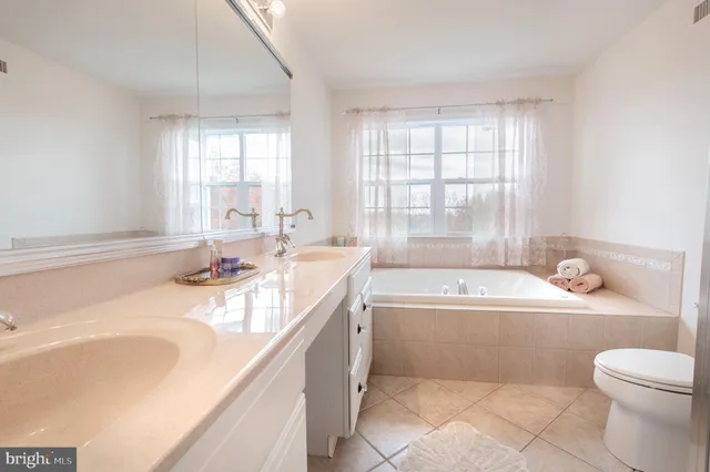 a bathroom with a granite countertop sink a toilet a bathtub and window