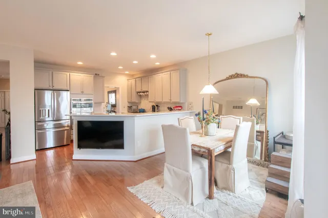 a kitchen with stainless steel appliances a white table chairs and a refrigerator