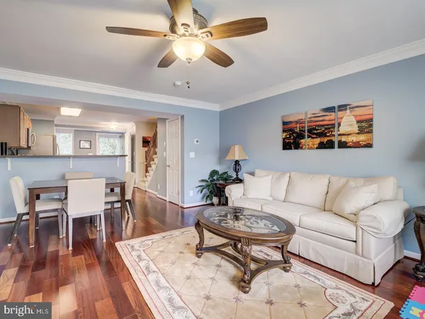 a living room with furniture a dining table and paintings on the wall with wooden floor